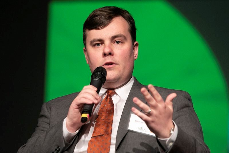 Michael C. McQueeny holding microphone at speaking engagement